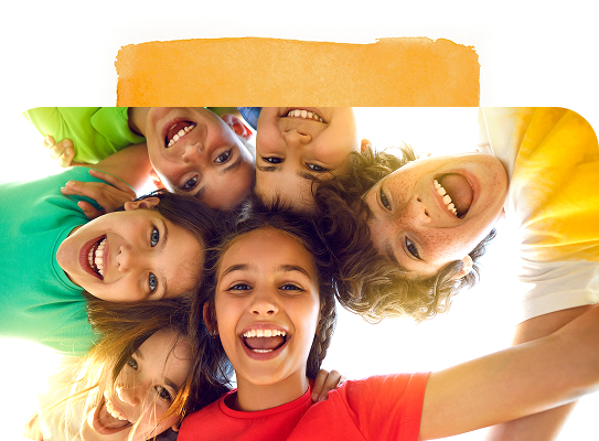 Group of smiling children in a circle looking down at the camera